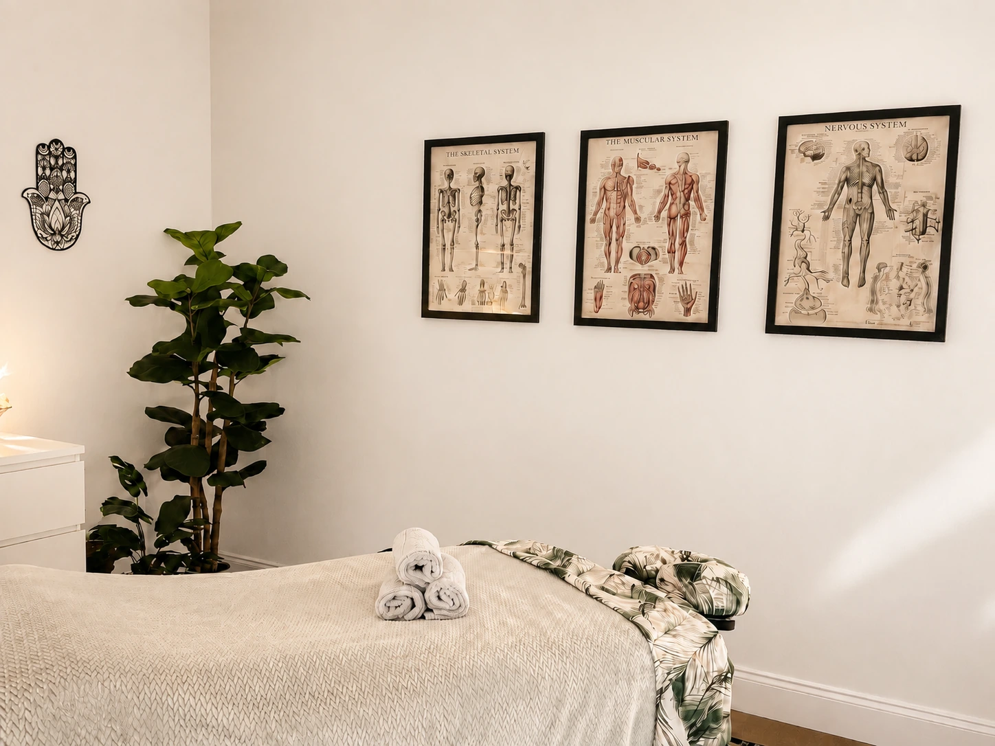 The treatment table with folded towels and a fiddle leaf fig.